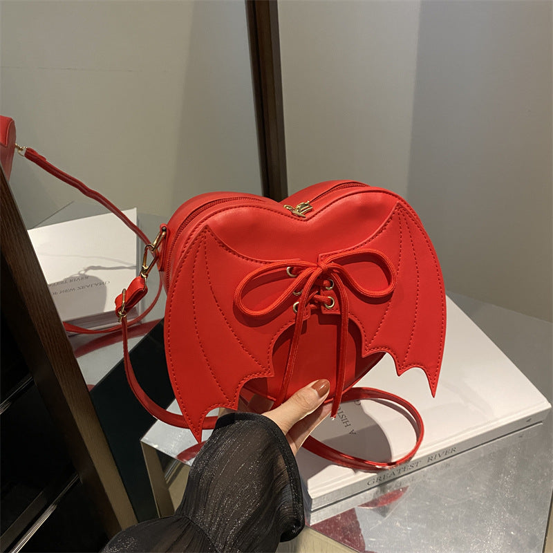 Bat-Wing Heart Crossbody Bag, red, held in hand