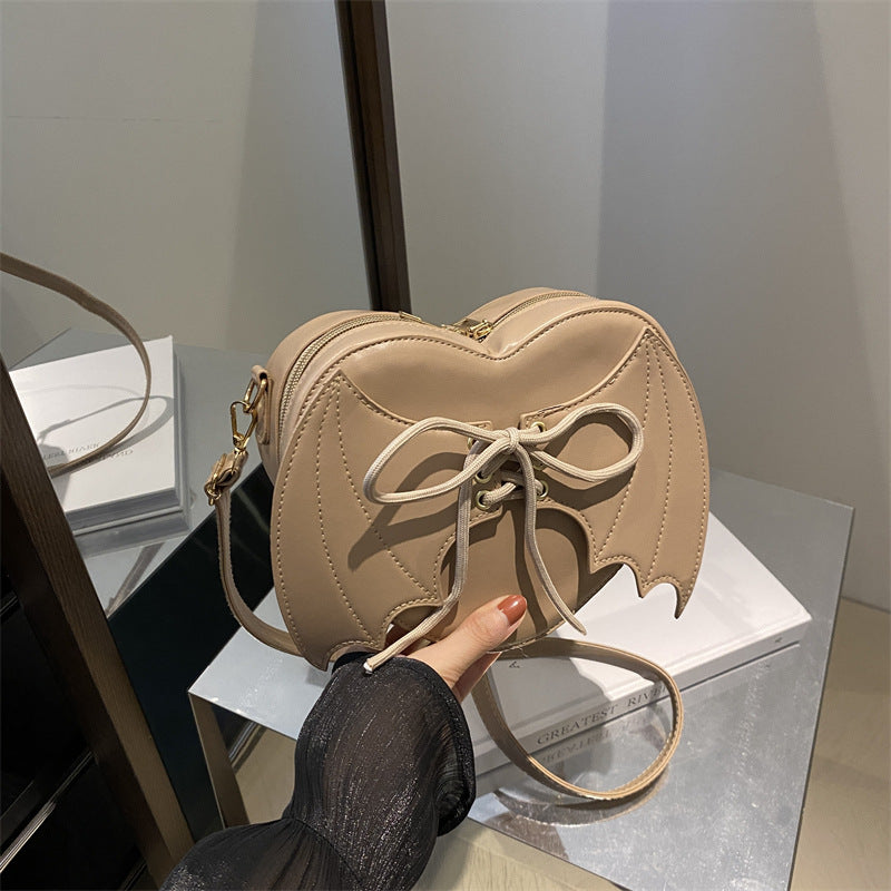 Bat-Wing Heart Crossbody Bag, khaki, held in hand
