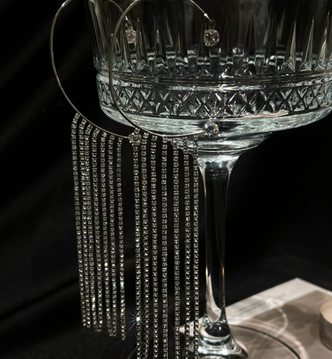 Rhinestone tassel ear cuff, silver-tone, on a glass
